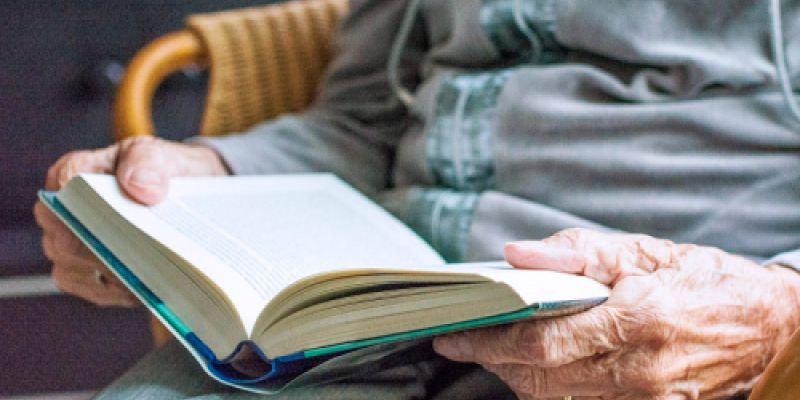 Persona mayor leyendo un libro sentada en Residencia Las Cumbres Persona mayor leyendo un libro sentada en Residencia Las Cumbres